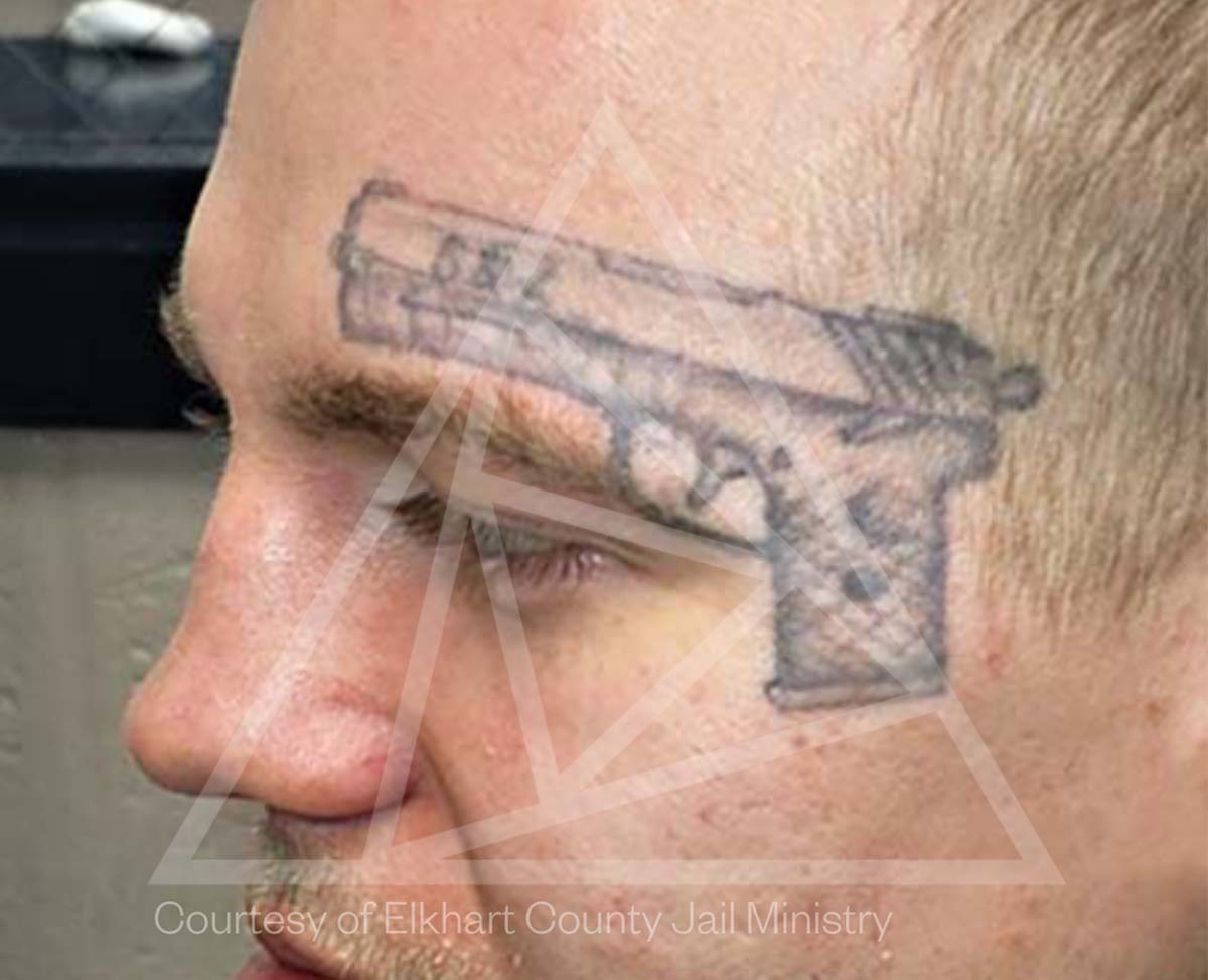 A tattoo of a gun above the eyebrow of a man